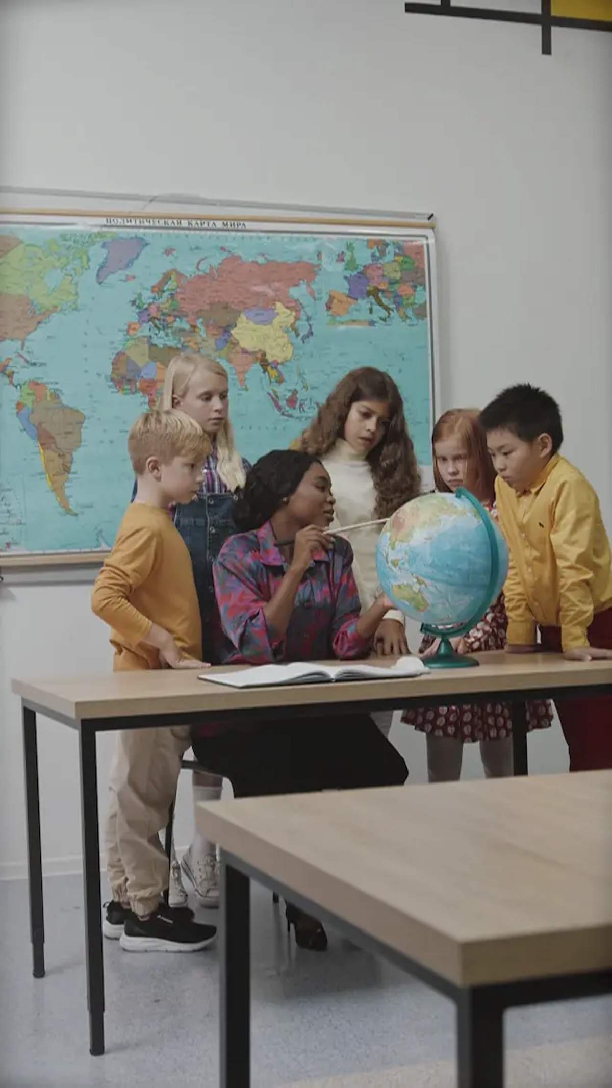 Students gathered around a globe in a classroom